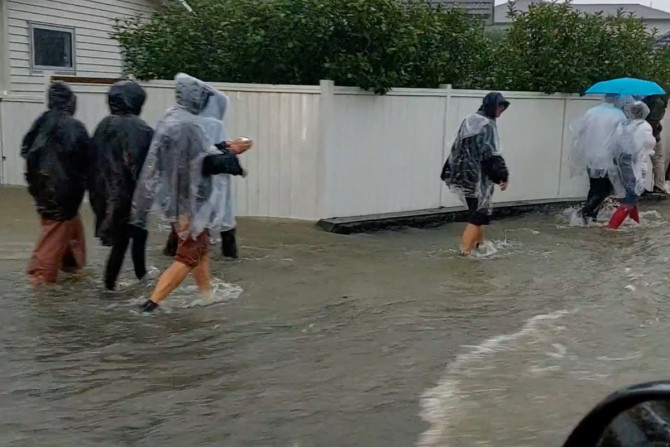 Menschen gehen auf einer überfluteten Straße, nachdem das Konzert von Elton John wegen schlechten Wetters in Auckland abgesagt wurde