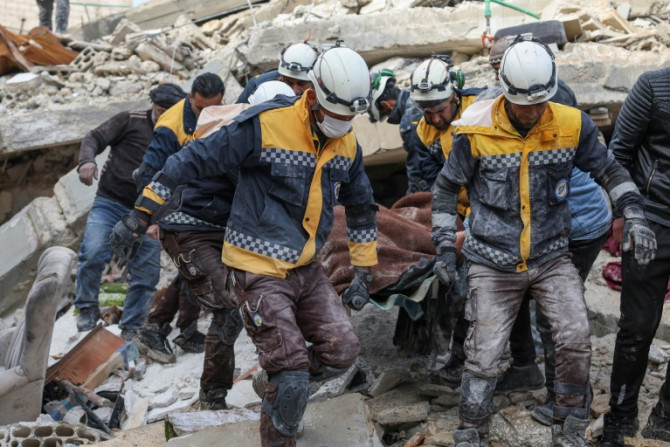 Angehörige der syrischen Zivilverteidigung oder Weißhelme tragen ein Bebenopfer aus den Trümmern