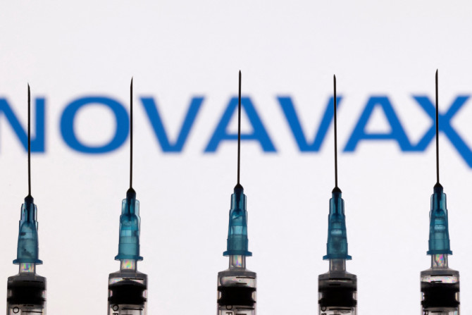 In dieser Abbildung sind Spritzen mit Nadeln vor einem angezeigten Novavax-Logo zu sehen