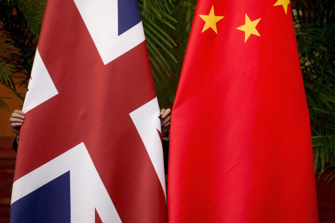 Ein Arbeiter passt britische und chinesische Nationalflaggen an, die für eine Unterzeichnungszeremonie beim siebten britisch-chinesischen Wirtschafts- und Finanzdialog „Roundtable on Public-Private Partnerships“ in Peking ausgestellt sind