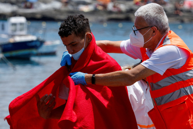 Ein Mitglied des Roten Kreuzes unterstützt einen Migranten nach dem Aussteigen von einem Schiff der spanischen Küstenwache im Hafen von Arguineguin