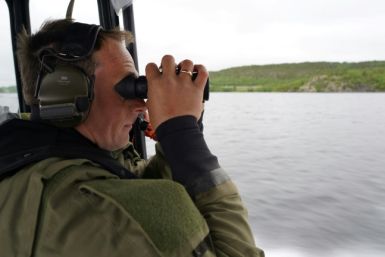 Der norwegische Sergeant Lars Erik Gausen scannt mit seinem Fernglas die russische Grenze, während er am Fluss Pasvik patrouilliert