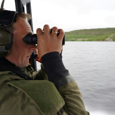 Der norwegische Sergeant Lars Erik Gausen scannt mit seinem Fernglas die russische Grenze, während er am Fluss Pasvik patrouilliert